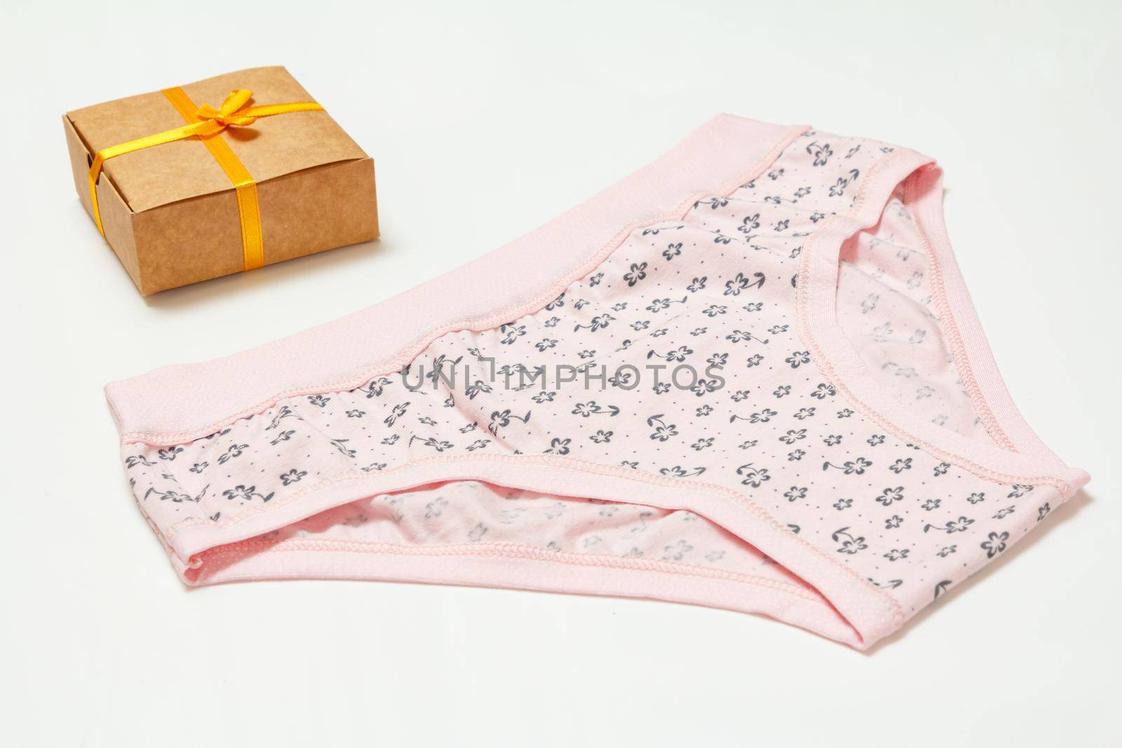 Pink cotton panties and a gift box on the white background. Woman underwear set. Top view.