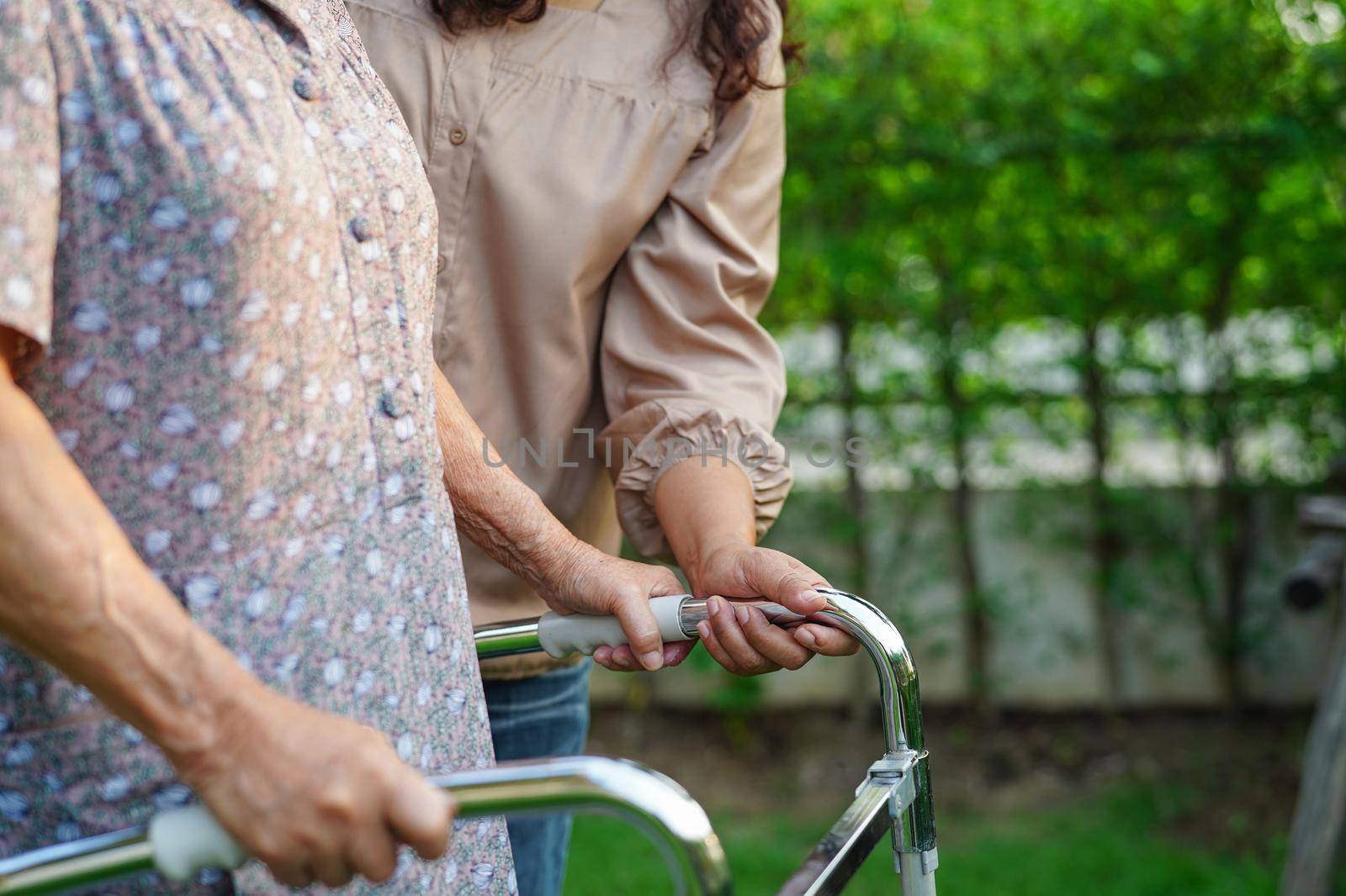 Caregiver help Asian elderly woman disability patient in nursing hospital, medical concept.