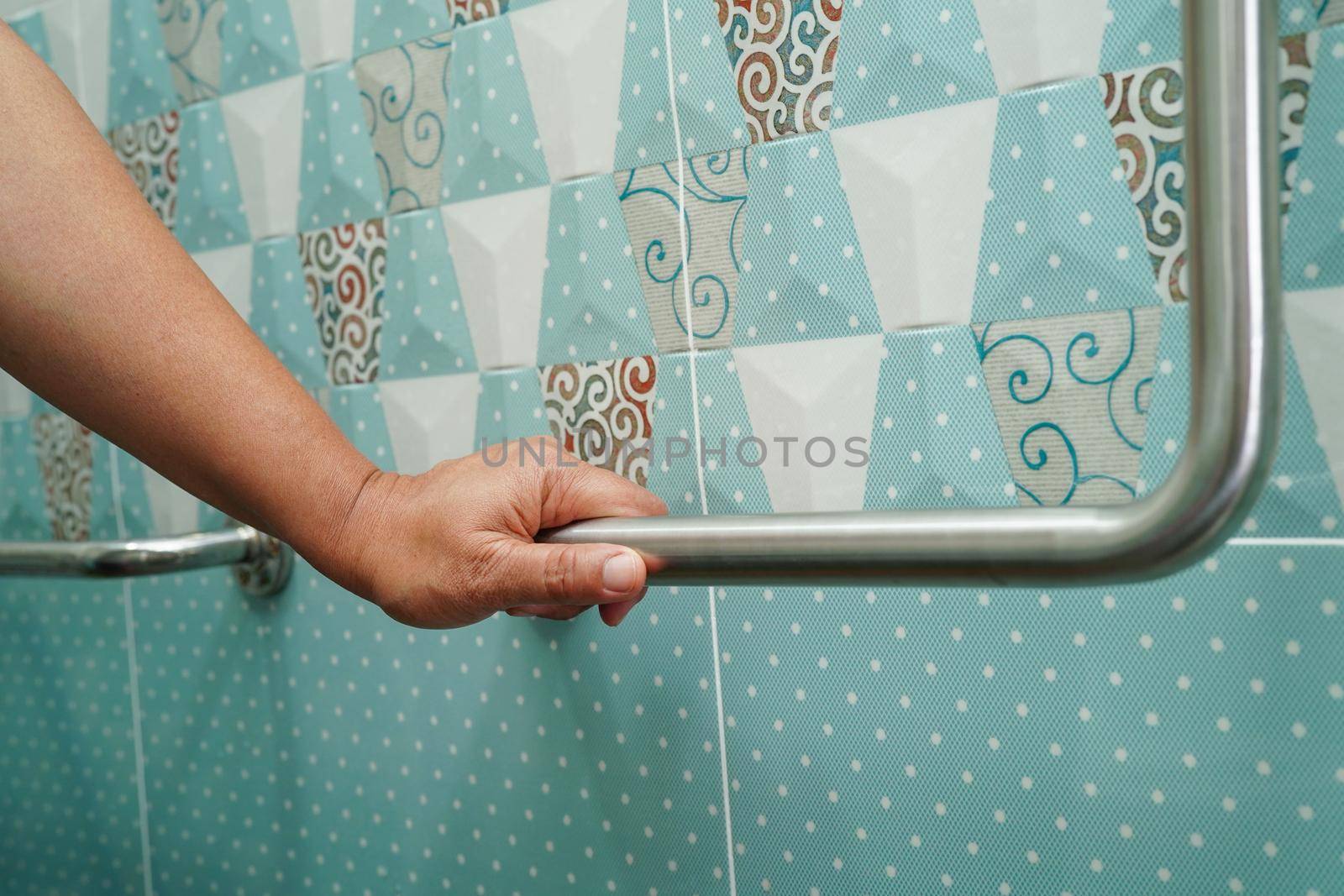 Asian woman patient use toilet support rail in bathroom, handrail safety grab bar, security in nursing hospital.