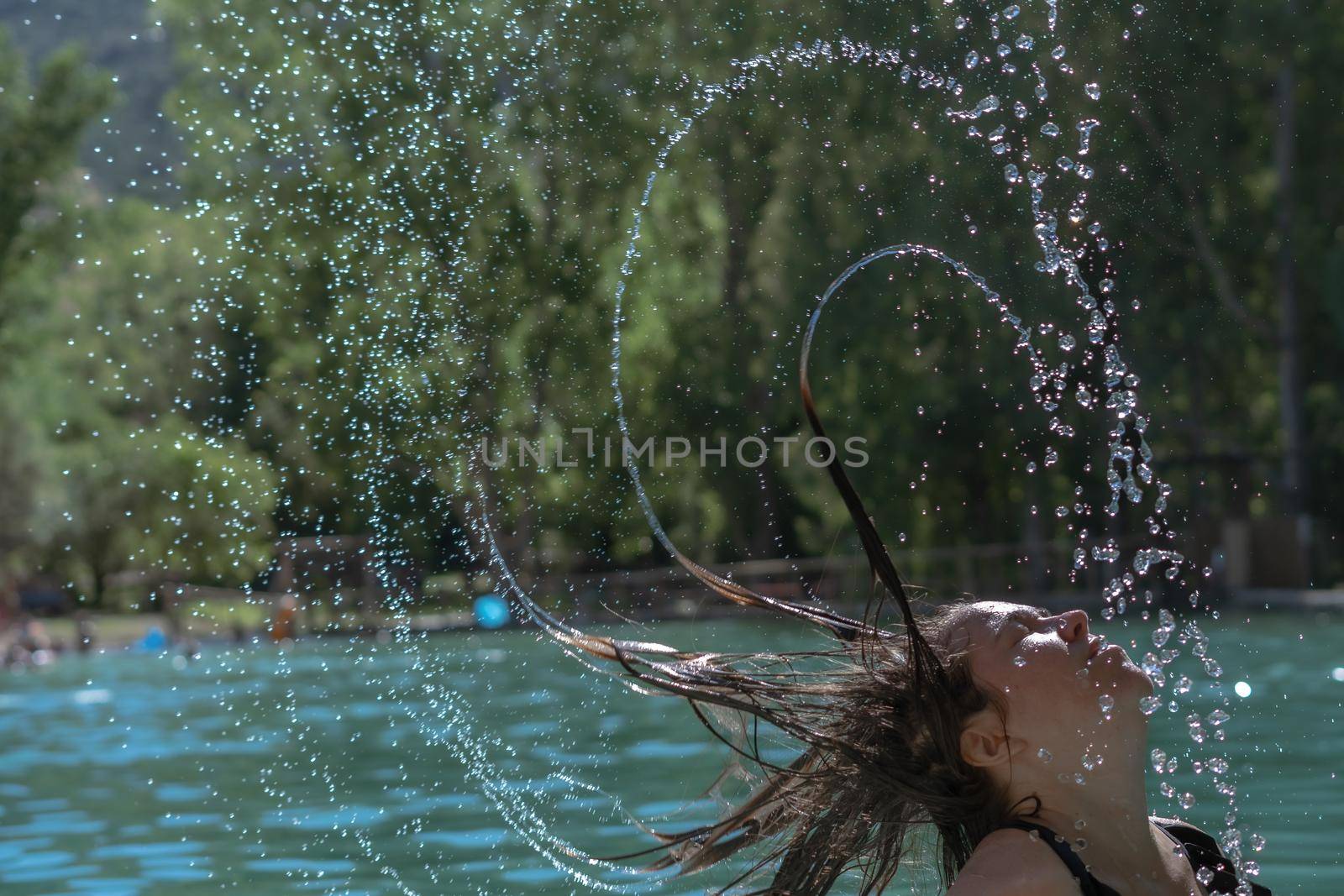 long-haired brunette girl waving her hair in the water splash effect by joseantona