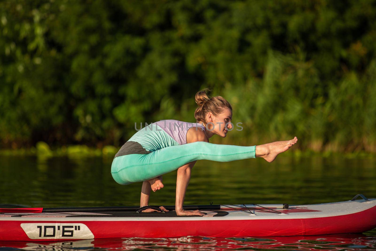 Young woman are doing yoga on a stand up paddle board SUP on a beautiful lake or river. The concept of a healthy lifestyle. Sport. Yoga. Hobby