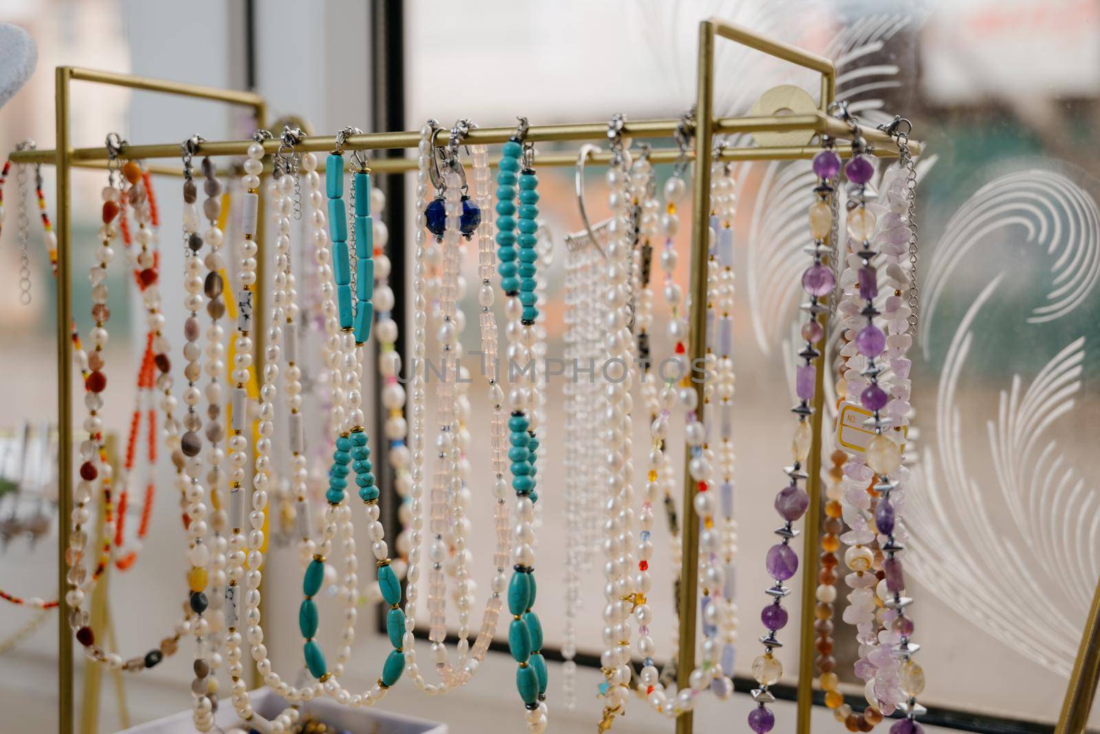 Shop window with necklaces and jewelry. Custome jewelry on display.Variety of colorful necklaces, bracelets, earrings, rings in window of costume jewelry store