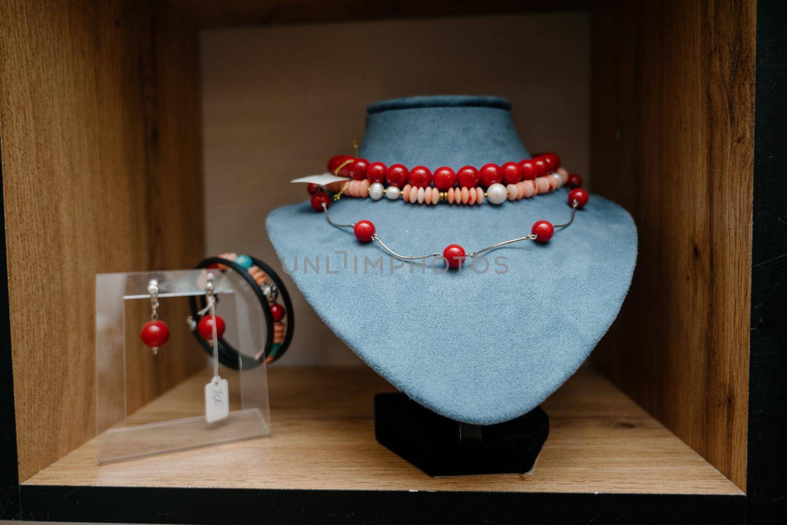 Shop window with necklaces and jewelry. Custome jewelry on display.Variety of colorful necklaces, bracelets, earrings, rings in window of costume jewelry store