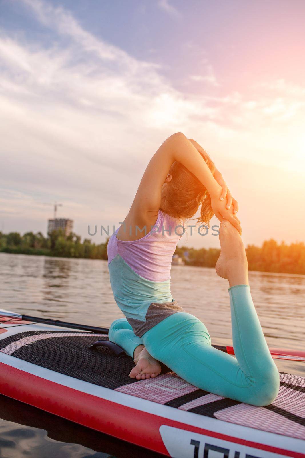 Young beautiful woman meditating in a sea at SUP paddleboarding. Healthy lifestyle. by nazarovsergey