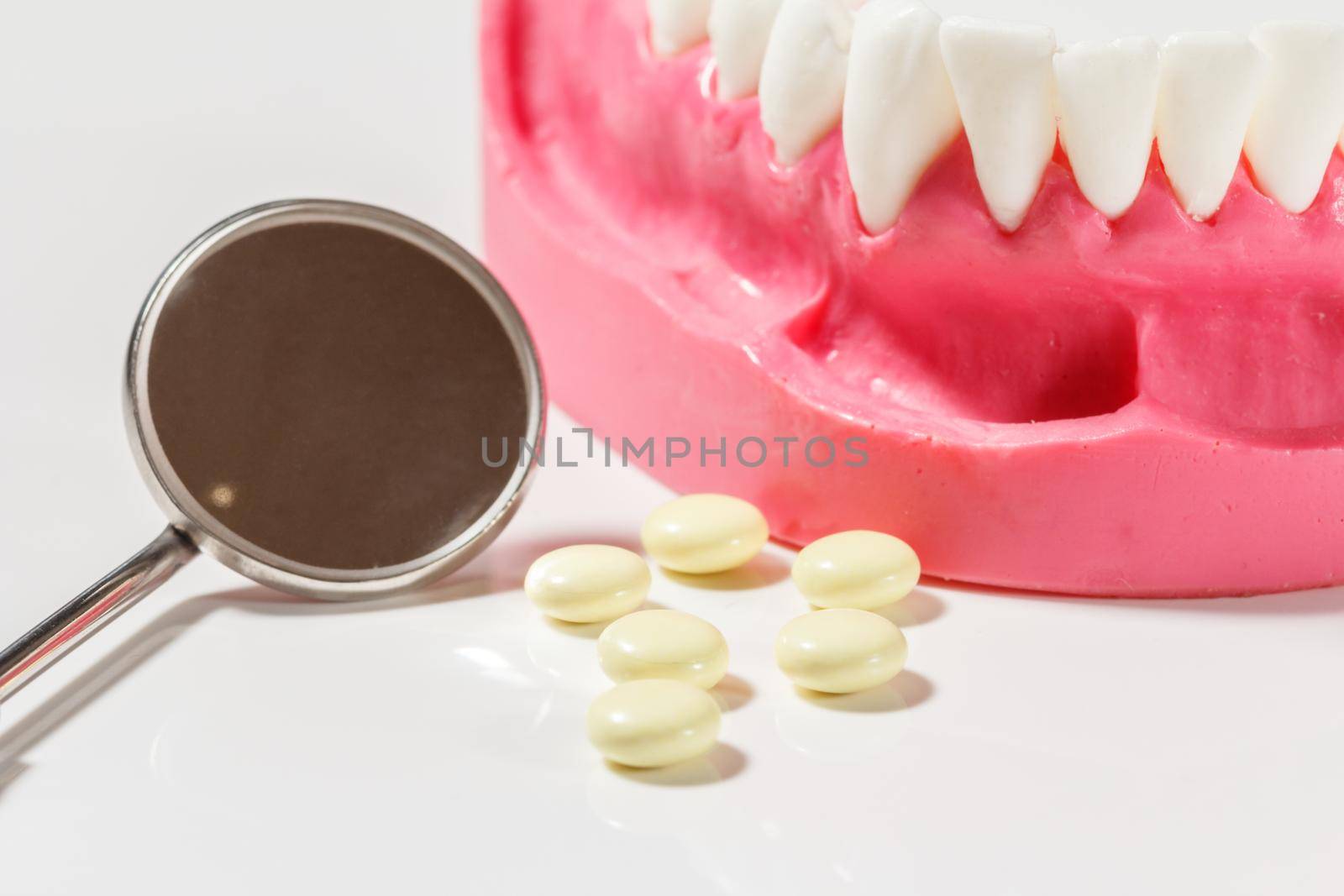 Layout of the human jaw, pills and a metal examination mirror. Layout to demonstrate the jaw to dental students.