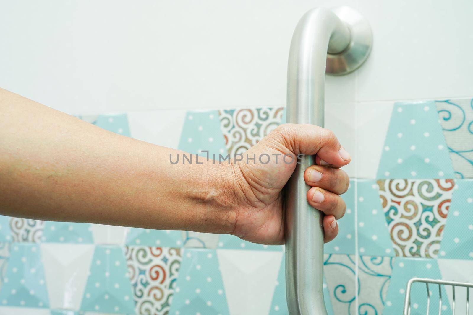 Asian woman patient use toilet support rail in bathroom, handrail safety grab bar, security in nursing hospital.