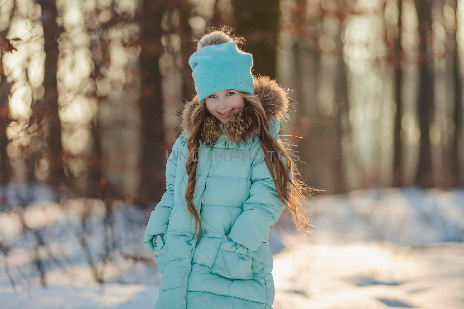 little girl in a winter forest and turquoise-colored clothes