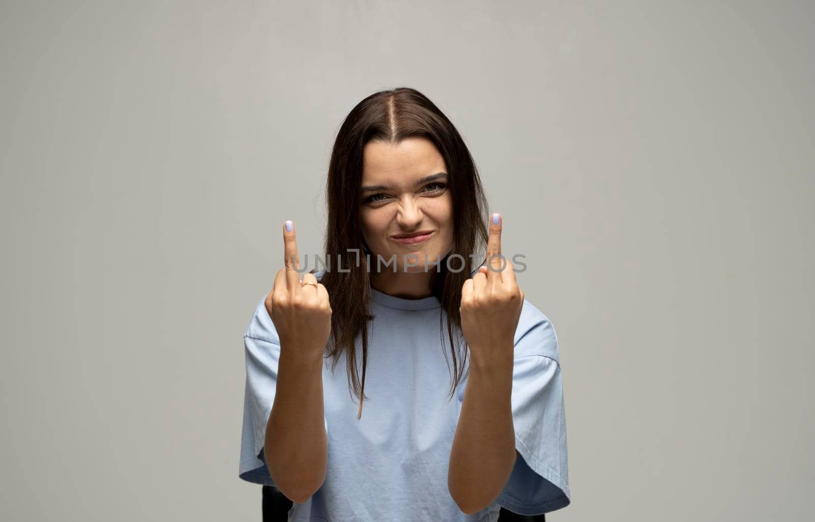 Portrait of rude vulgar woman showing middle fingers, impolite gesture of disrespect, looking with aggression hate on white background