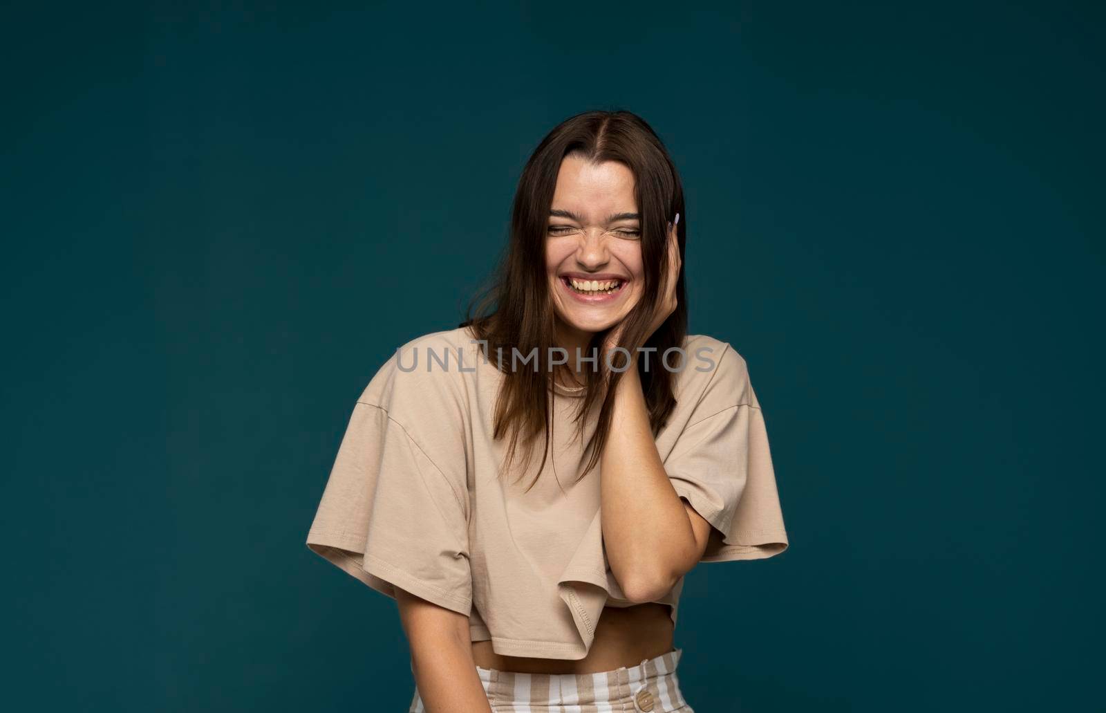 Positive human emotions. Headshot of happy emotional teenage brunette girl with long haircut laughing from the bottom of her heart