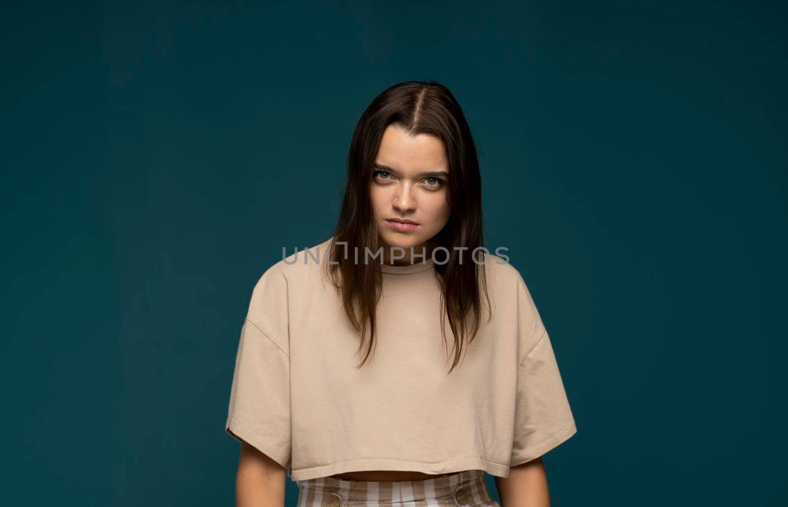 Portrait of an upset unsatisfied brunette woman looking in the camera isolated over blue background. by vovsht