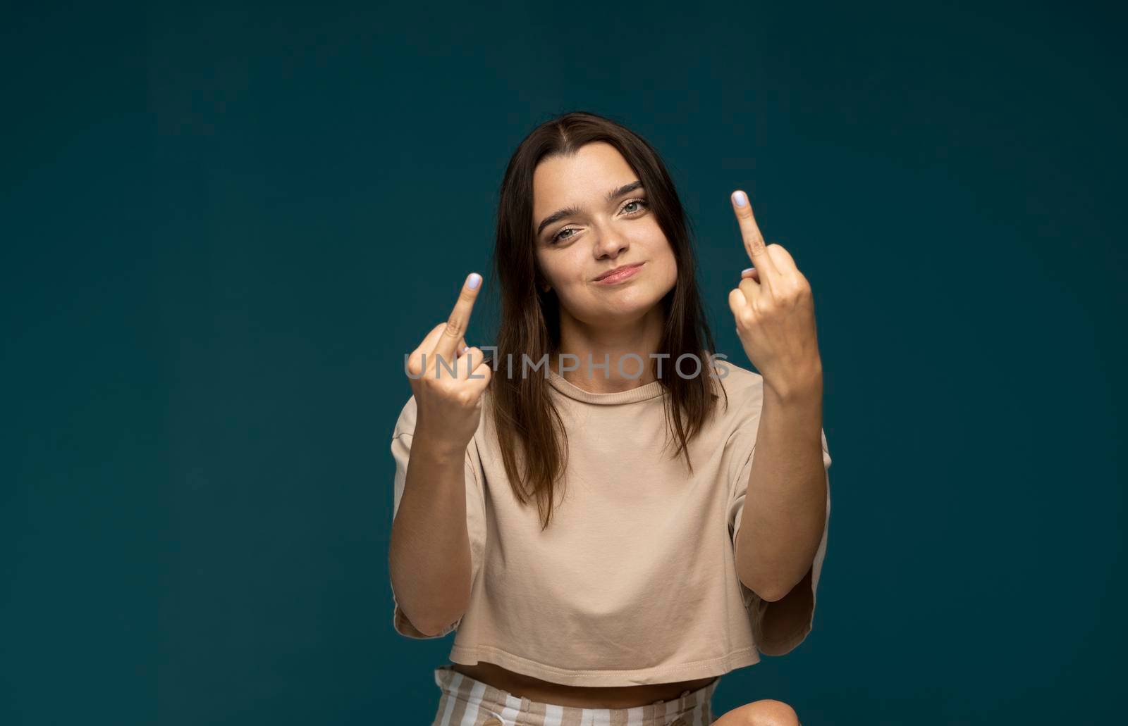 Portrait of crazy angry brunette woman wearing casual style beige t-shirt showing middle finger, rude gesture, face full of hatred and resentment. by vovsht