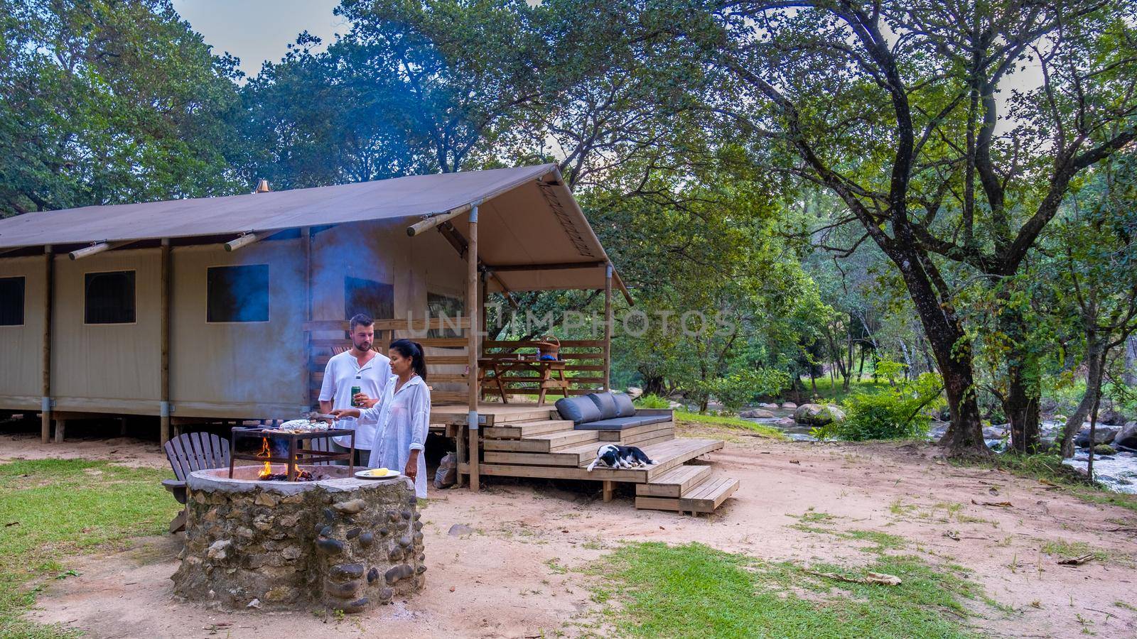 Budget Safari tent in South Africa for family vacations in nature, Safari tented camp in green forest bush nature. Asian women and European men camping