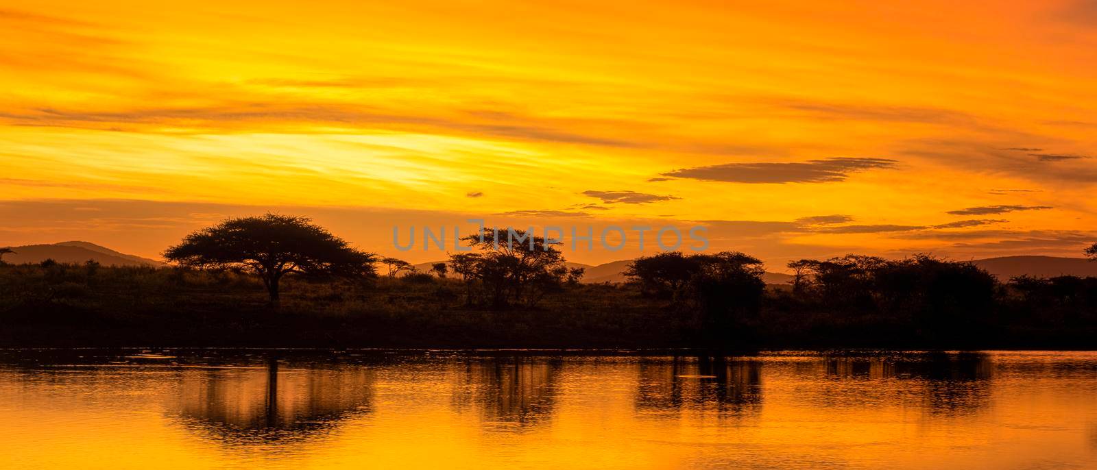 African sunset with lake trees and mountains, sunset by a water lake in Savannah South Africa. colorful sunset