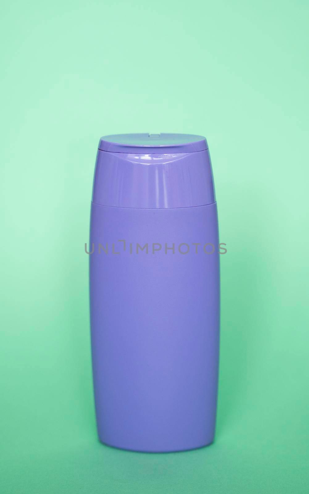 Violet plastic bottle of body care and beauty products. Studio photography of plastic bottle for shampoo, shower gel, creme isolated on green background. by vovsht
