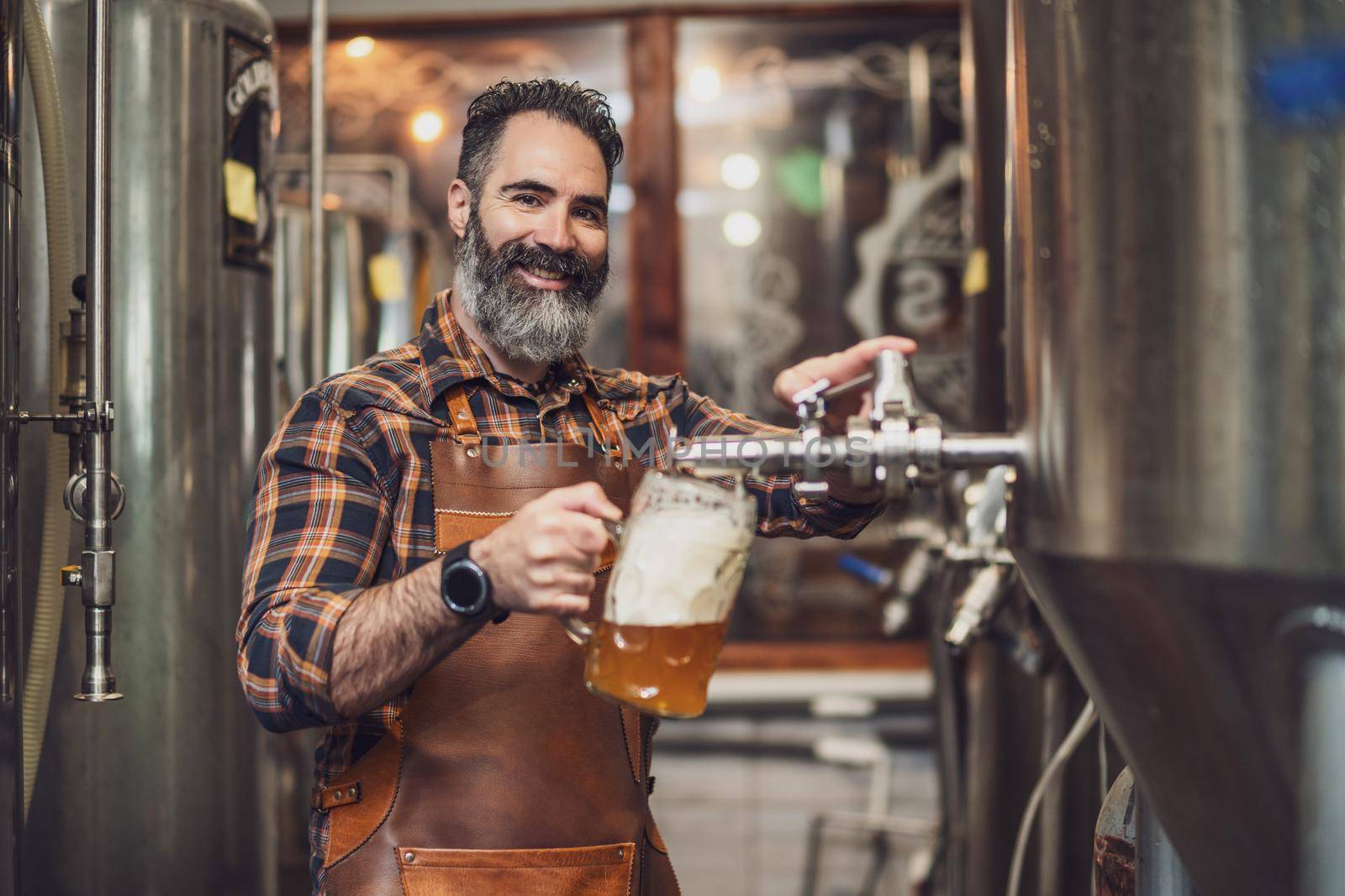 Brewery master tasting beer in production facility. Small family business, production of craft beer.