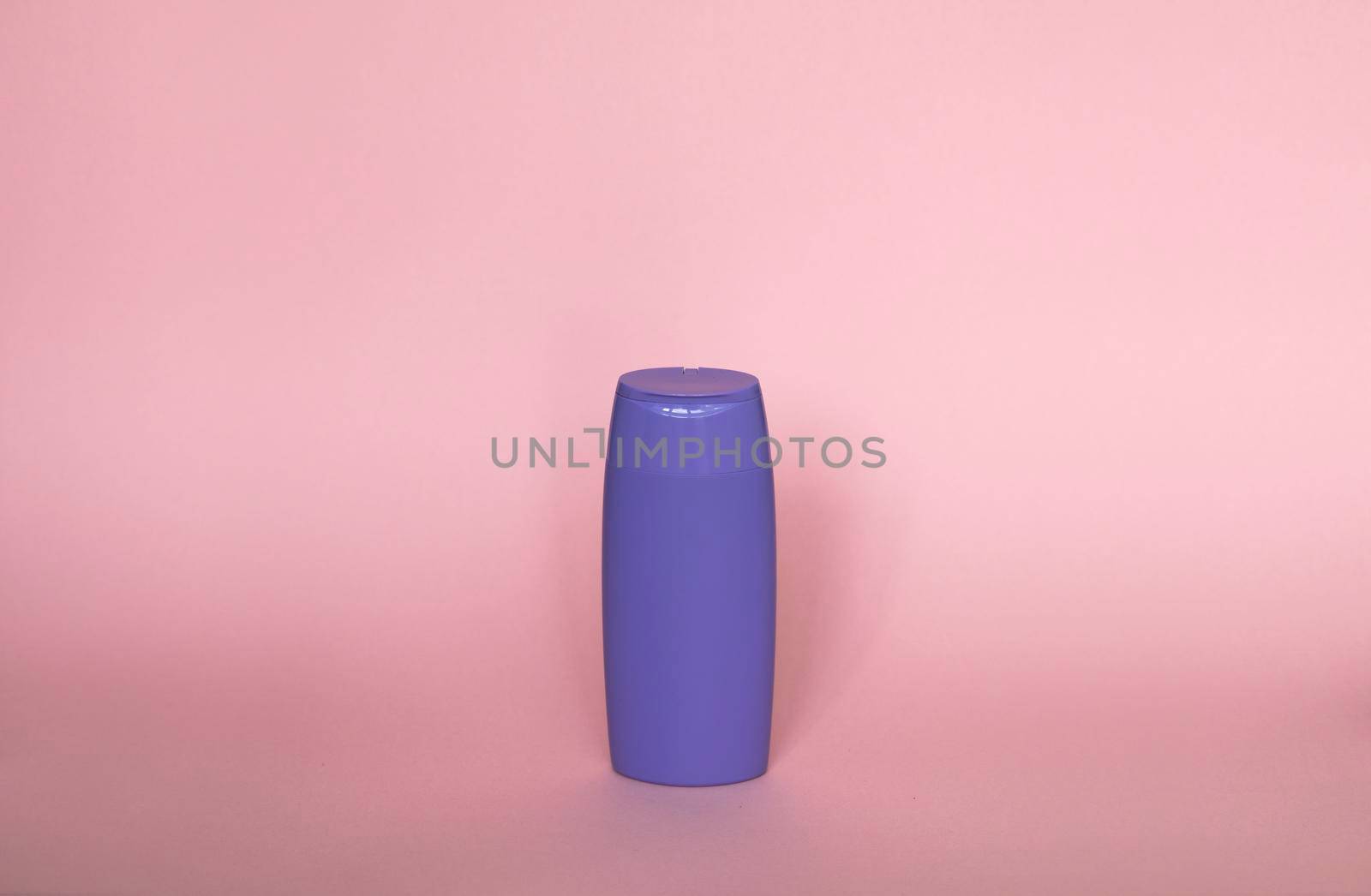 Violet plastic bottle of body care and beauty products. Studio photography of plastic bottle for shampoo, shower gel, creme isolated on pink background. by vovsht