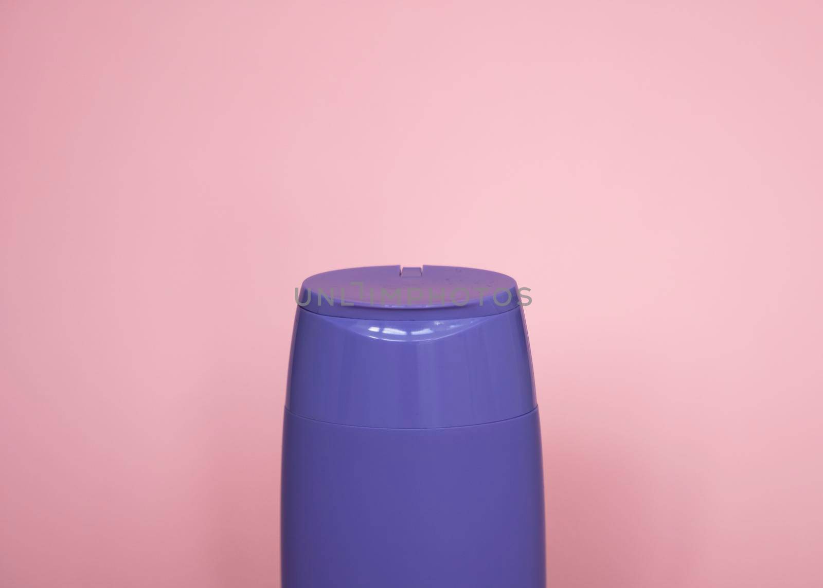 Violet plastic bottle of body care and beauty products. Studio photography of plastic bottle for shampoo, shower gel, creme isolated on pink background