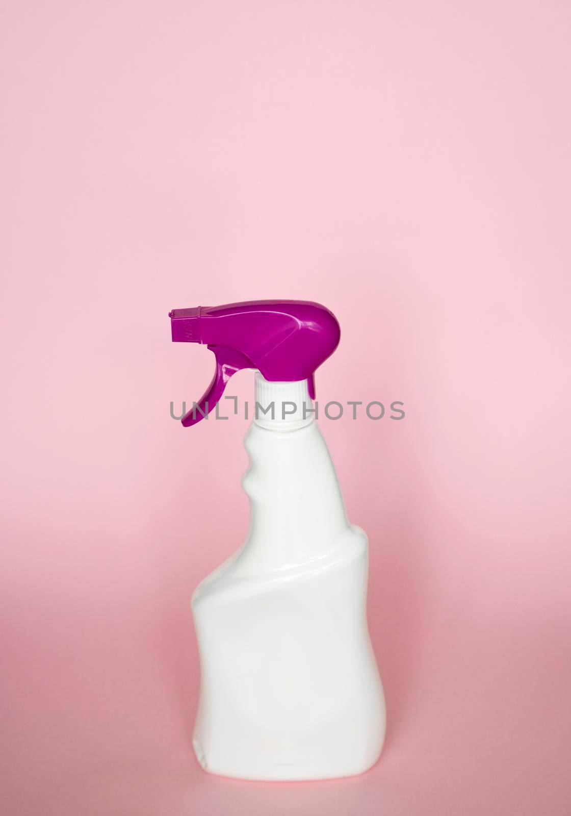 White plastic spray bottle for liquid cleaning products isolated on pink background. Packaging mockup bottle with violet sprayer
