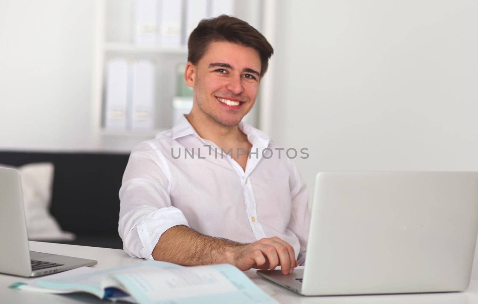 Young man sitting in chair and working on laptop computer .