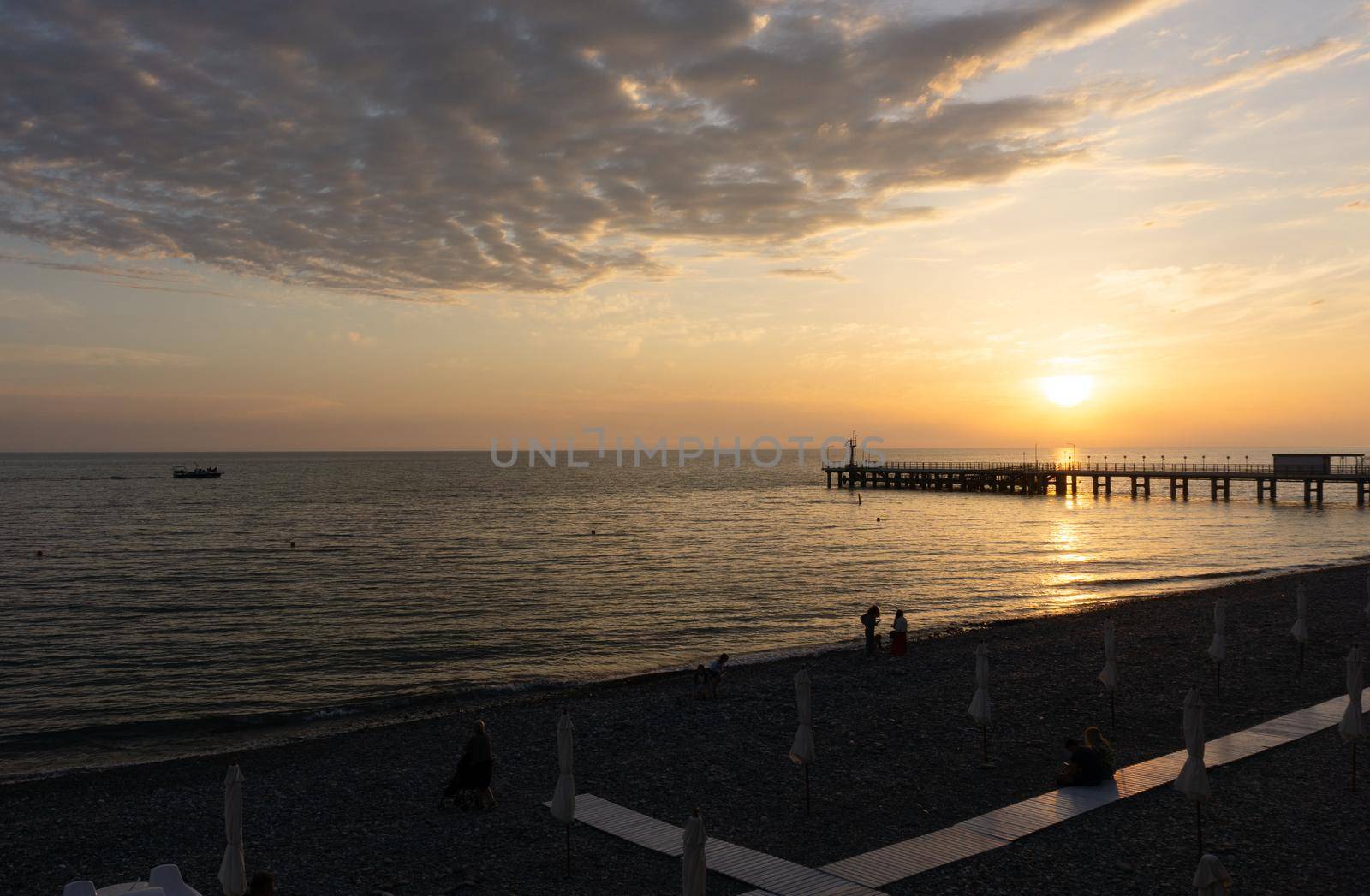 LAZAREVSKOE, SOCHI, RUSSIA - MAY, 26, 2021: Orange saturated sunset with silhouettes of people on the background of the sun.