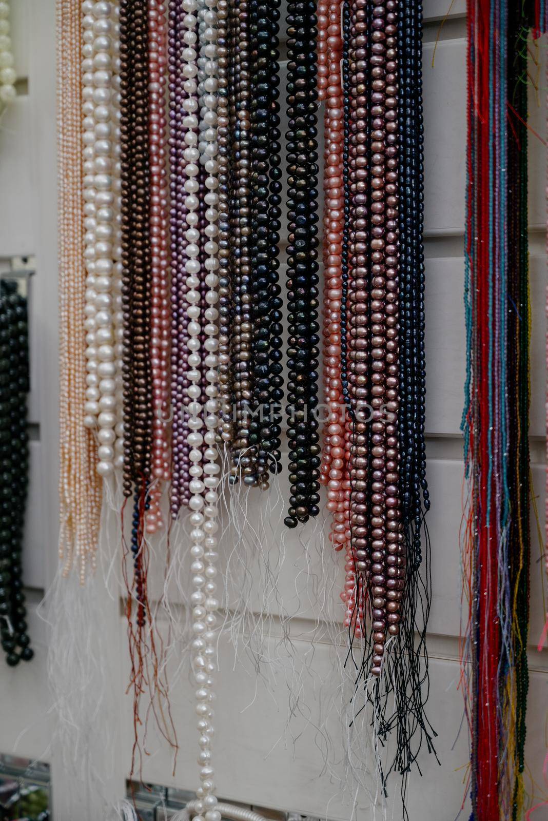 Shop window with necklaces and jewelry. Custome jewelry on display.Variety of colorful necklaces, bracelets, earrings, rings in window of costume jewelry store