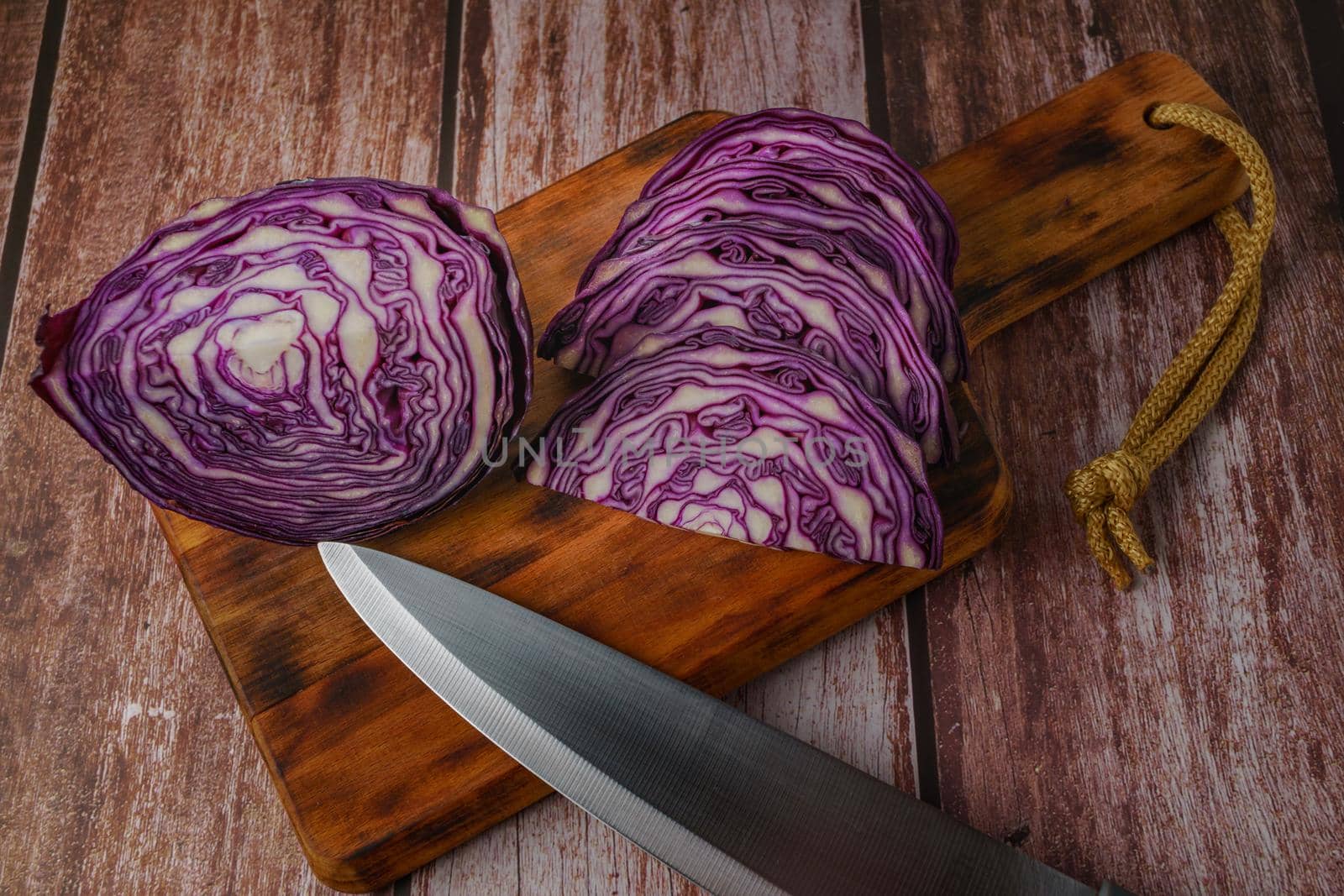 close-up of a red cabbage or purple cabbage cut with a knife on a wooden board