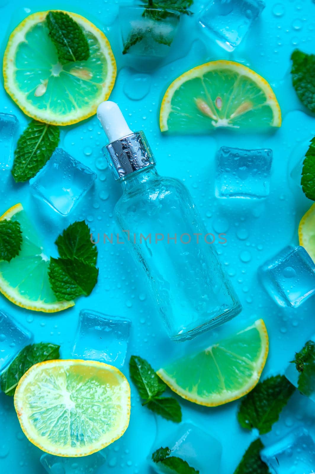 Bottle with cosmetics on a mint background with ice cubes and lemon. Selective focus. Spa.