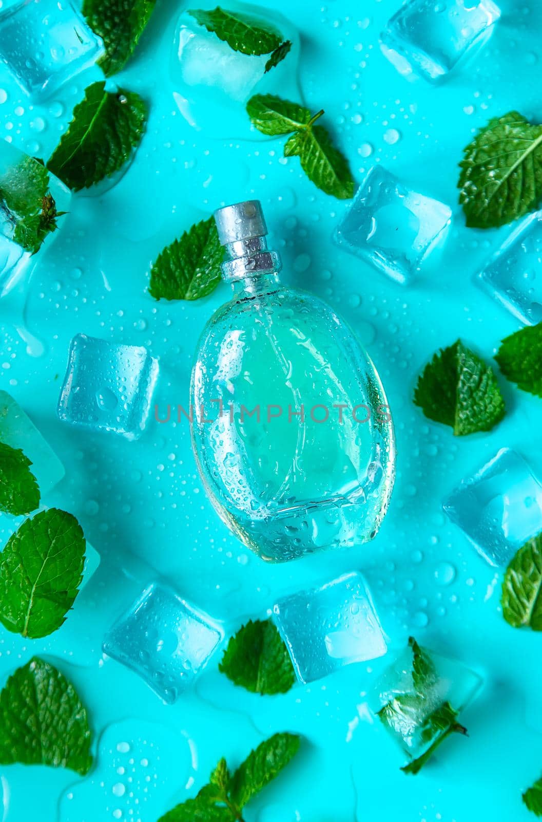 Perfume on a blue background with ice cubes and mint. Selective focus. Spa.