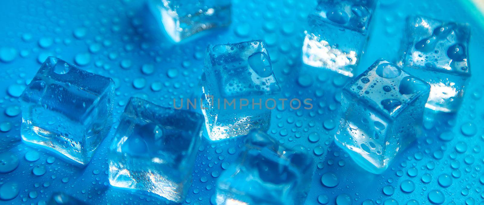 Ice cubes on a blue background. Selective focus. by yanadjana
