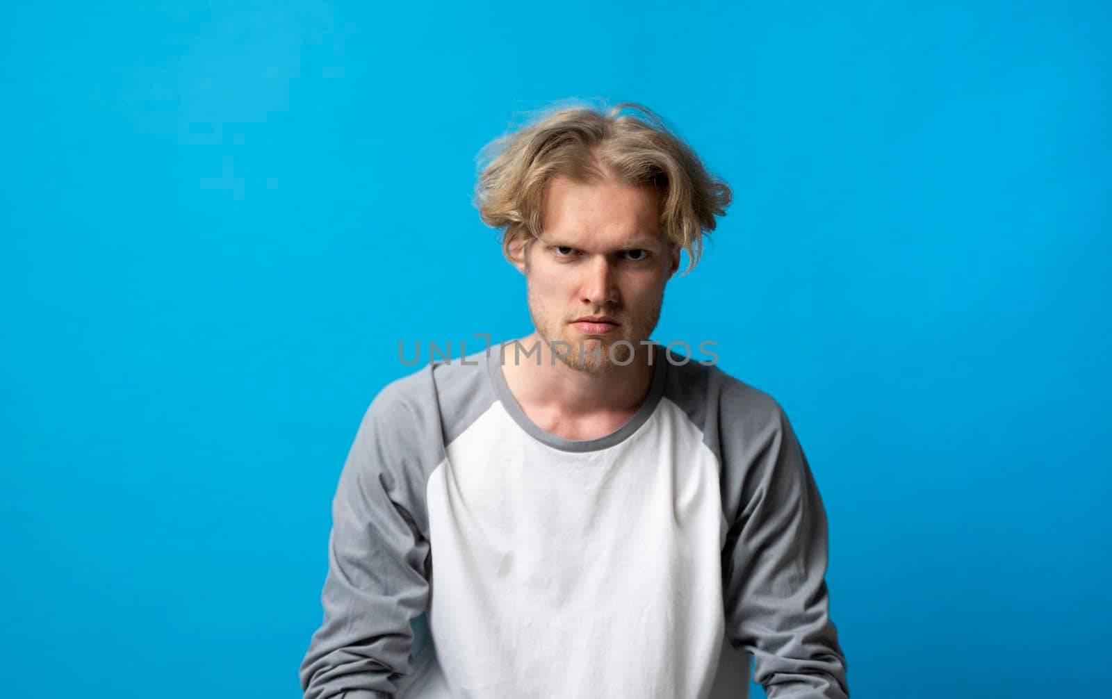 Portrait of an upset unsatisfied man standing with arms and a backs and looking in the camera isolated over white background. Negative human emotions facial expression feelings attitude. by vovsht