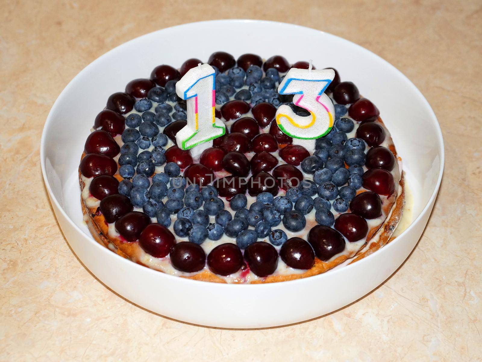 candles with number 13 on cherry cake, thirteenth birthday close-up