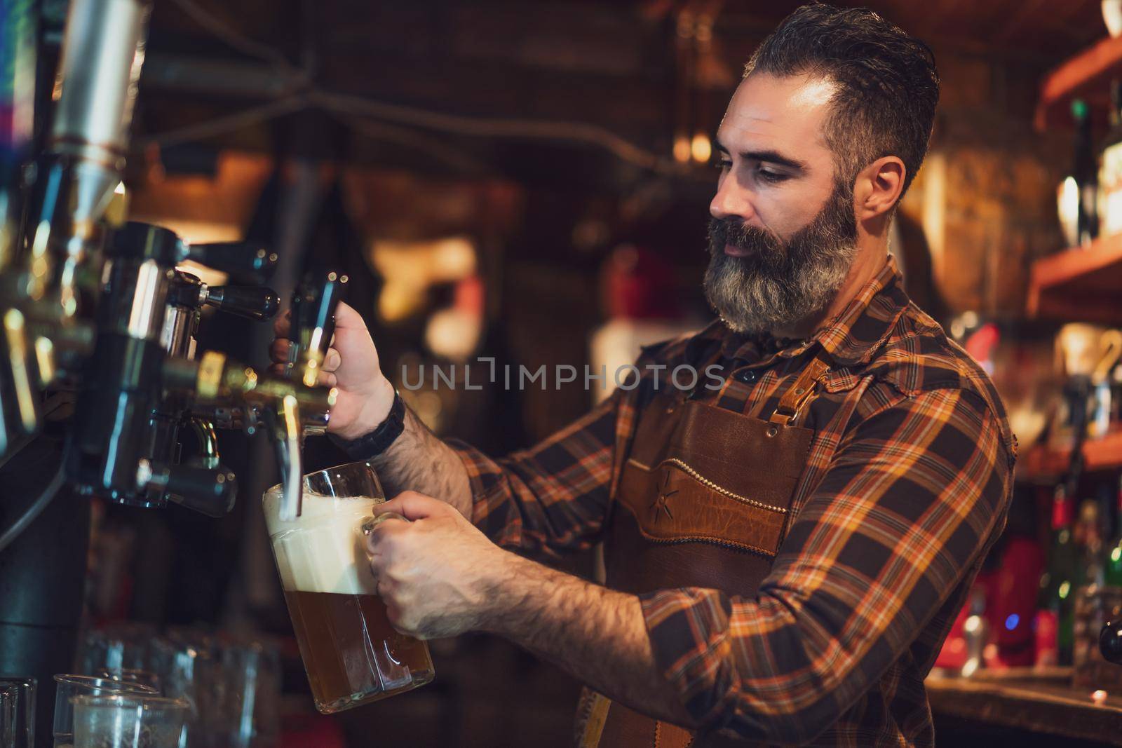 Portrait of barmen at pub. He pours beer into a beer glass.