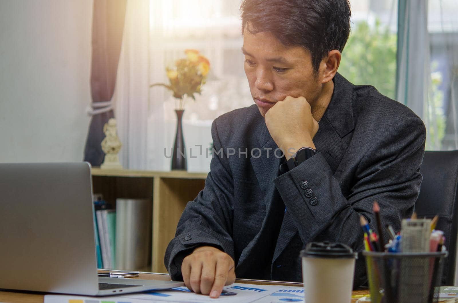 businessman looks at document financial and economic investment chart and graph paperwork marketing is sitting at laptop computer.