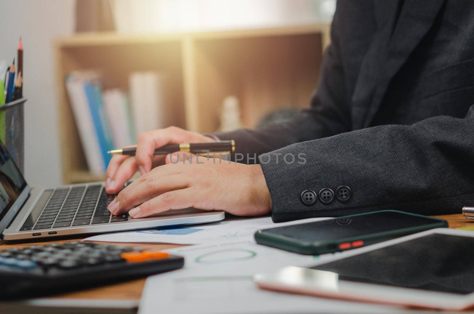 Businessman person pointing document graph financial marketing report and paperwork chart analysis investment with computer laptop on desk at office.