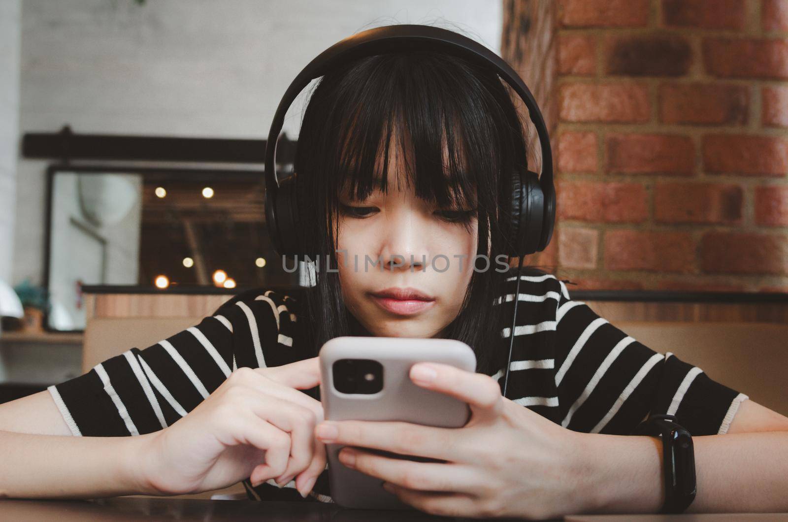 Teenage girl wearing headphones and holding a cell phone smartphone social media relaxing on the sofa.