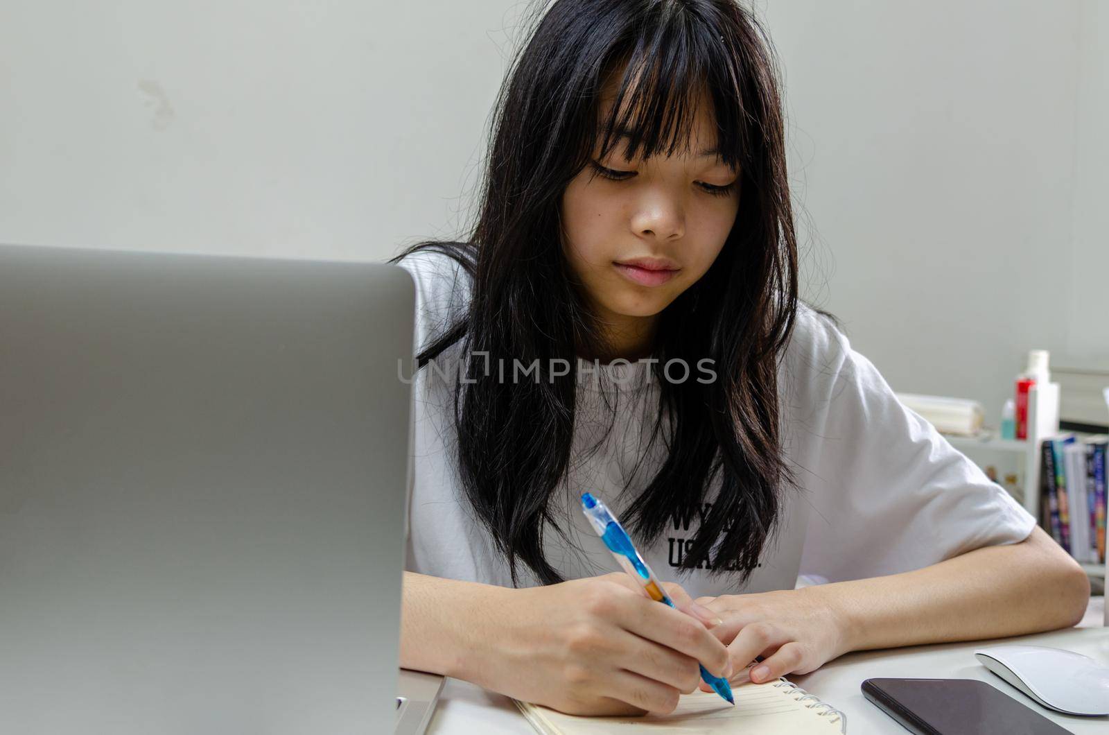 girl holding pen writing book study learning digital internet video online computer laptop at home.
