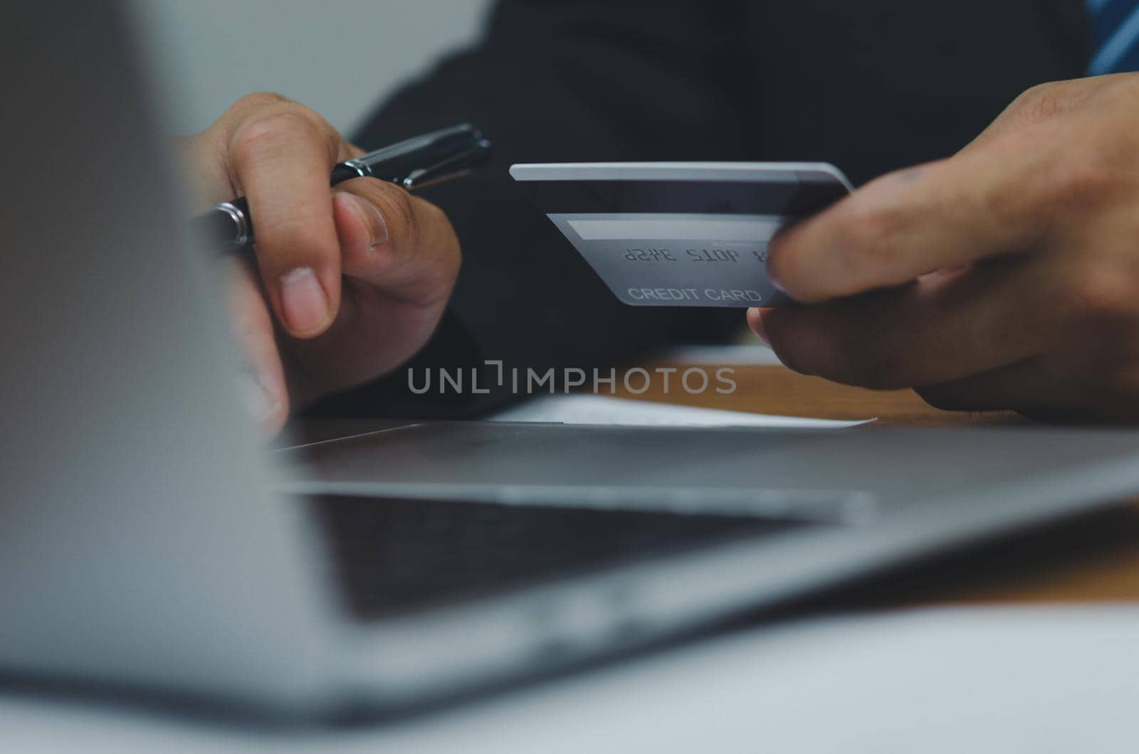Man hand holding credit card using Internet technology digital to pay for his purchases and shopping online on a computer.