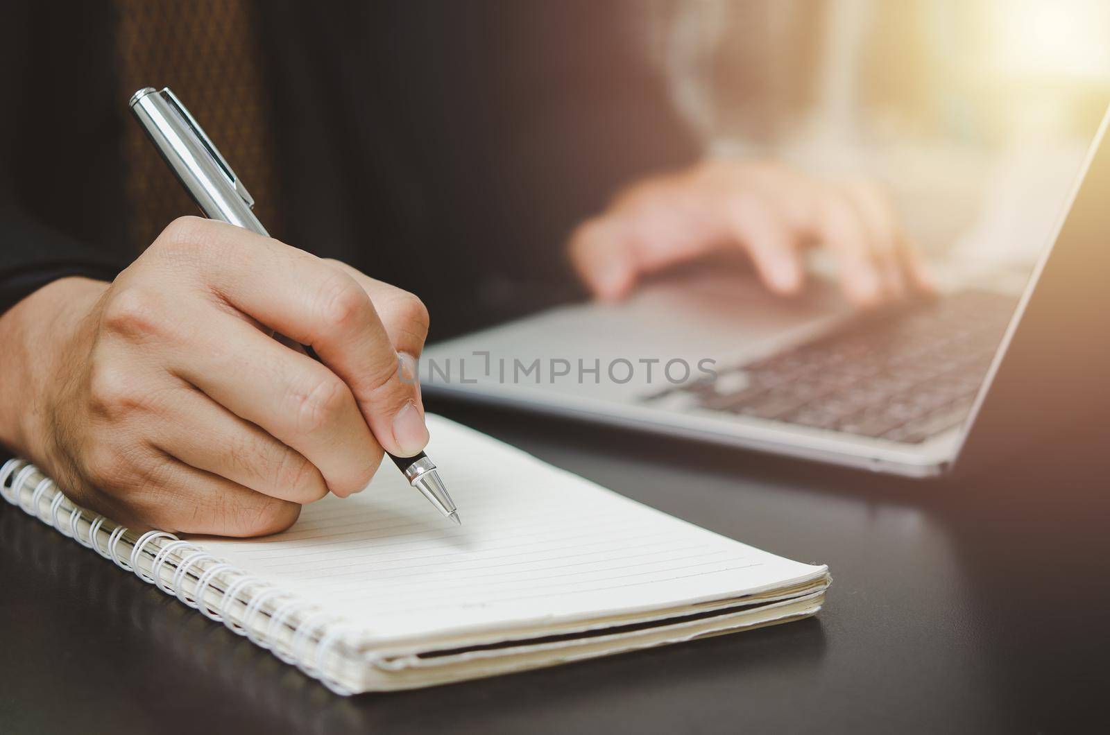 person man holding pen write plan or idea on book with computer laptop on desk.
