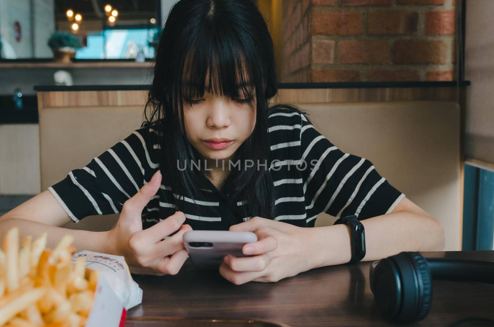 Teenage girl wearing headphones and holding a cell phone smartphone social media relaxing on the sofa. by aoo3771