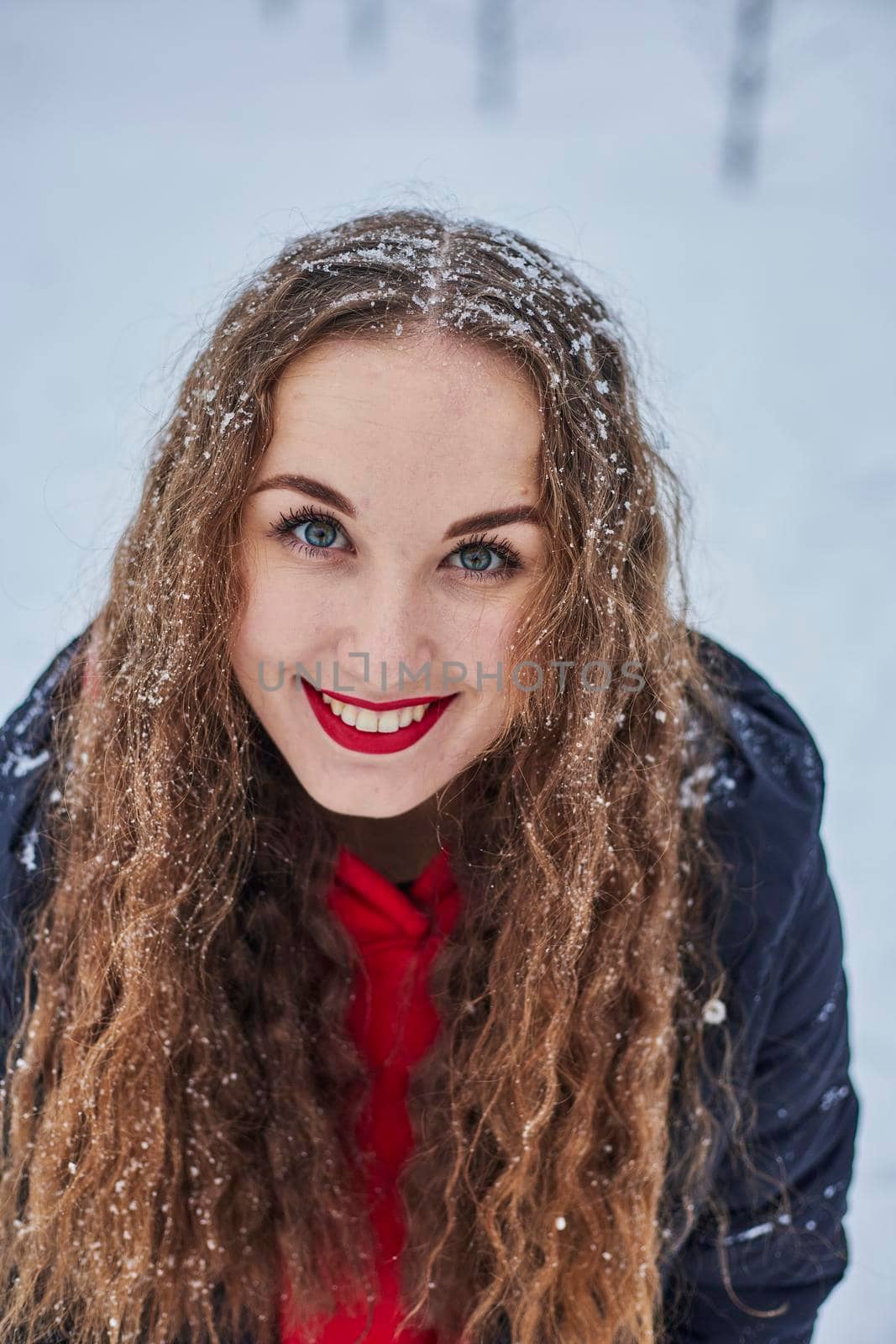 a young happy woman is having fun in a winter park, throwing snow, it is cold in her hands, the emissions are off scale