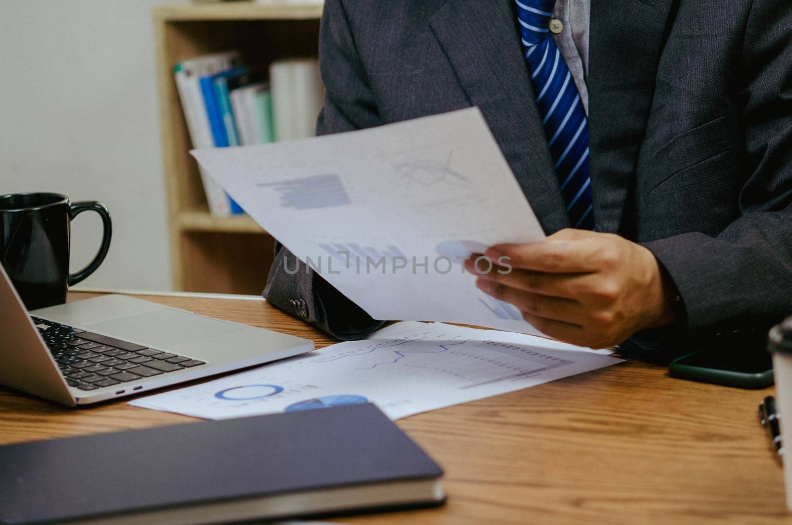 Businessman holding paperwork document graph report accounting and finance investment on desk. by aoo3771