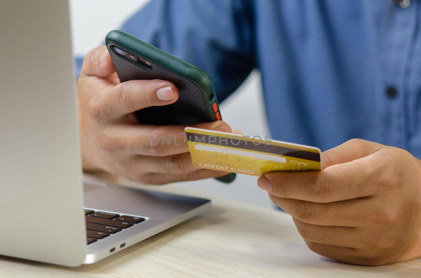 Man hand holding credit card and mobile smart phone with computer laptop.Business finance banking internet and shopping online commerce technology concept.