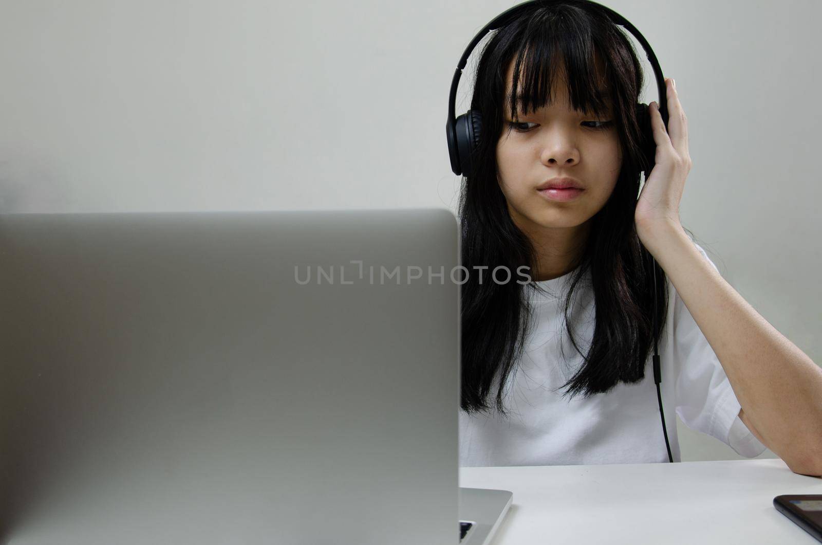 girl wearing headphones studying online with computer laptop and listen to relaxing music or play internet social media at home. by aoo3771