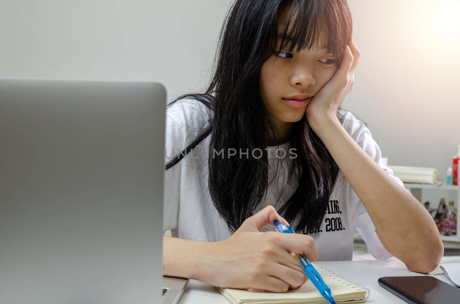 girl holding pen writing book study learning digital internet video online computer laptop at home.