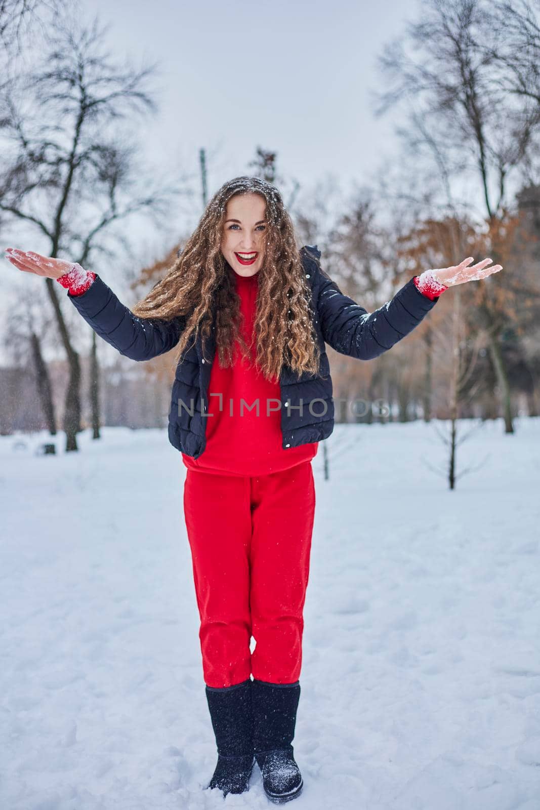 a young happy woman is having fun in a winter park, throwing snow, it is cold in her hands, the emissions are off scale. by mosfet_ua