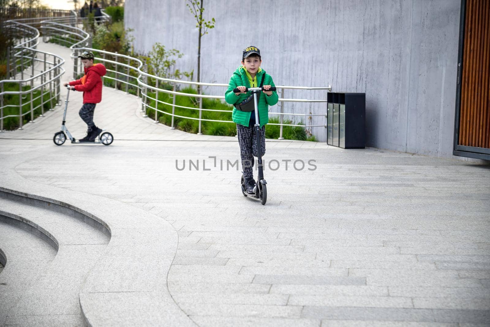 Happy family lifestyle and holiday concept. little boy and his sibling brother riding scooters, walking in city, street. Having fun.