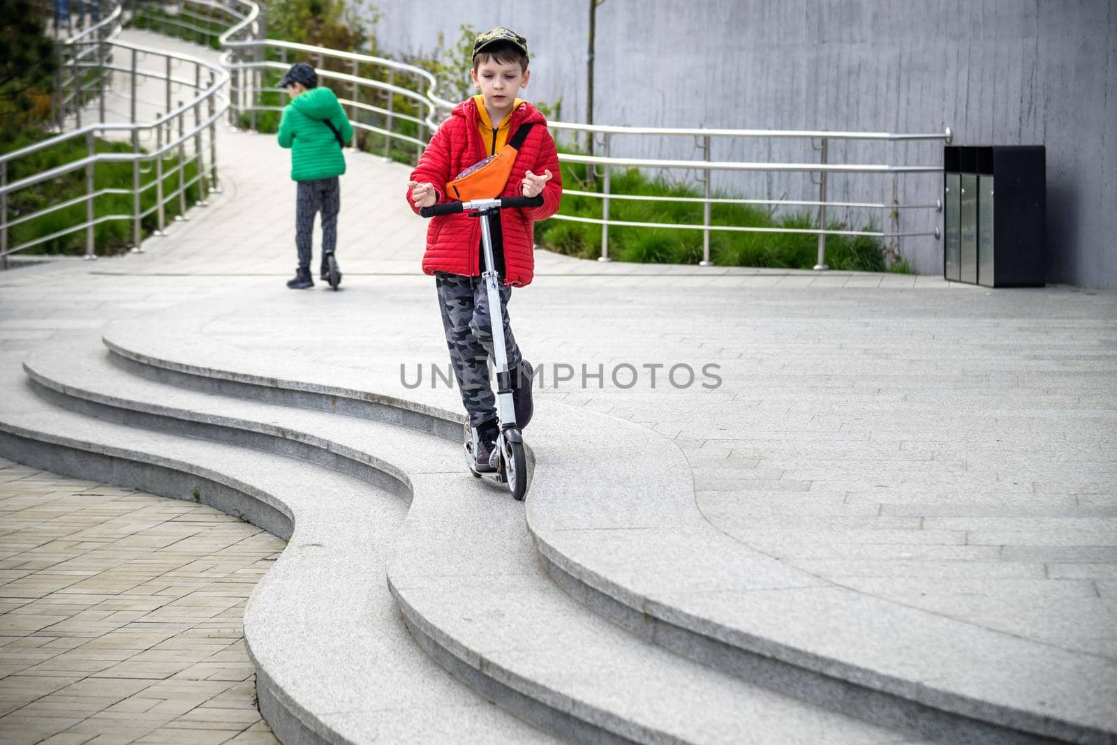 Happy family lifestyle and holiday concept. little boy and his sibling brother riding scooters, walking in city, street. Having fun.