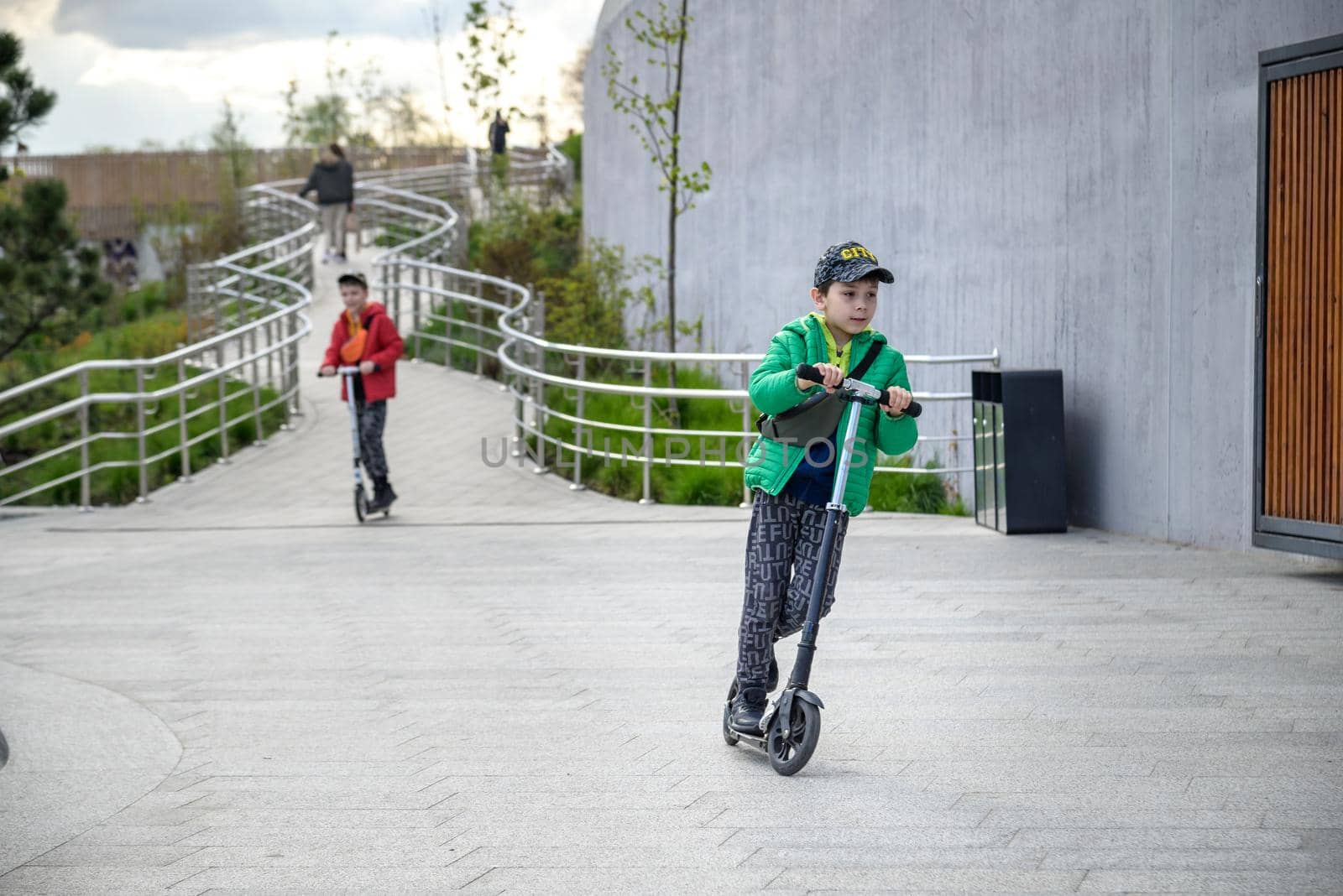 Happy family lifestyle and holiday concept. little boy and his sibling brother riding scooters, walking in city, street. Having fun.