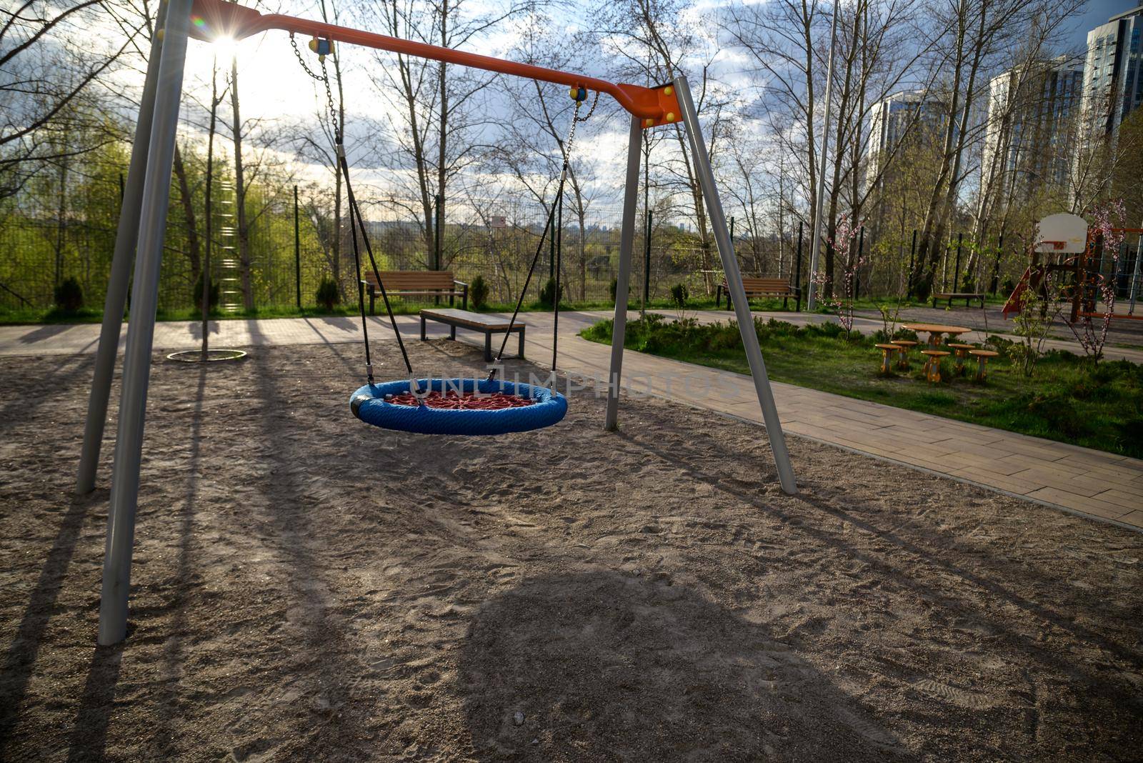 Round swing seat made of mesh in playground. Empty blue and red rope web nest for swinging closeup. children's swing High quality photo.