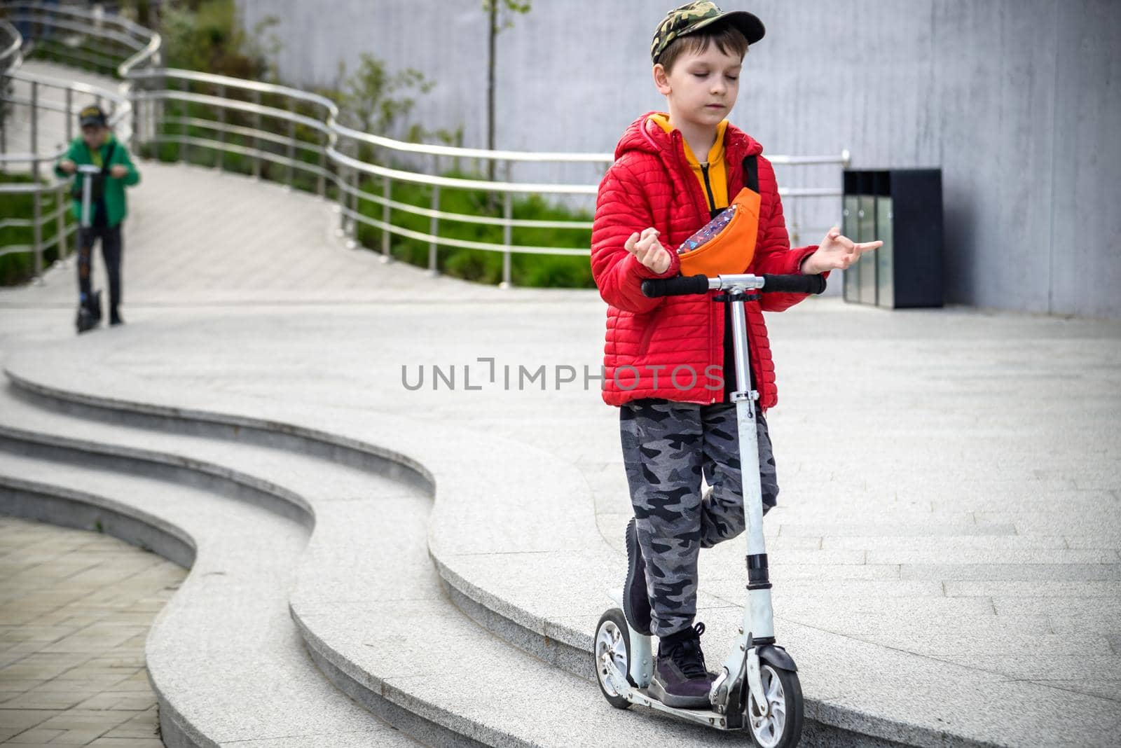 Happy family lifestyle and holiday concept. little boy and his sibling brother riding scooters, walking in city, street. Having fun by Kobysh